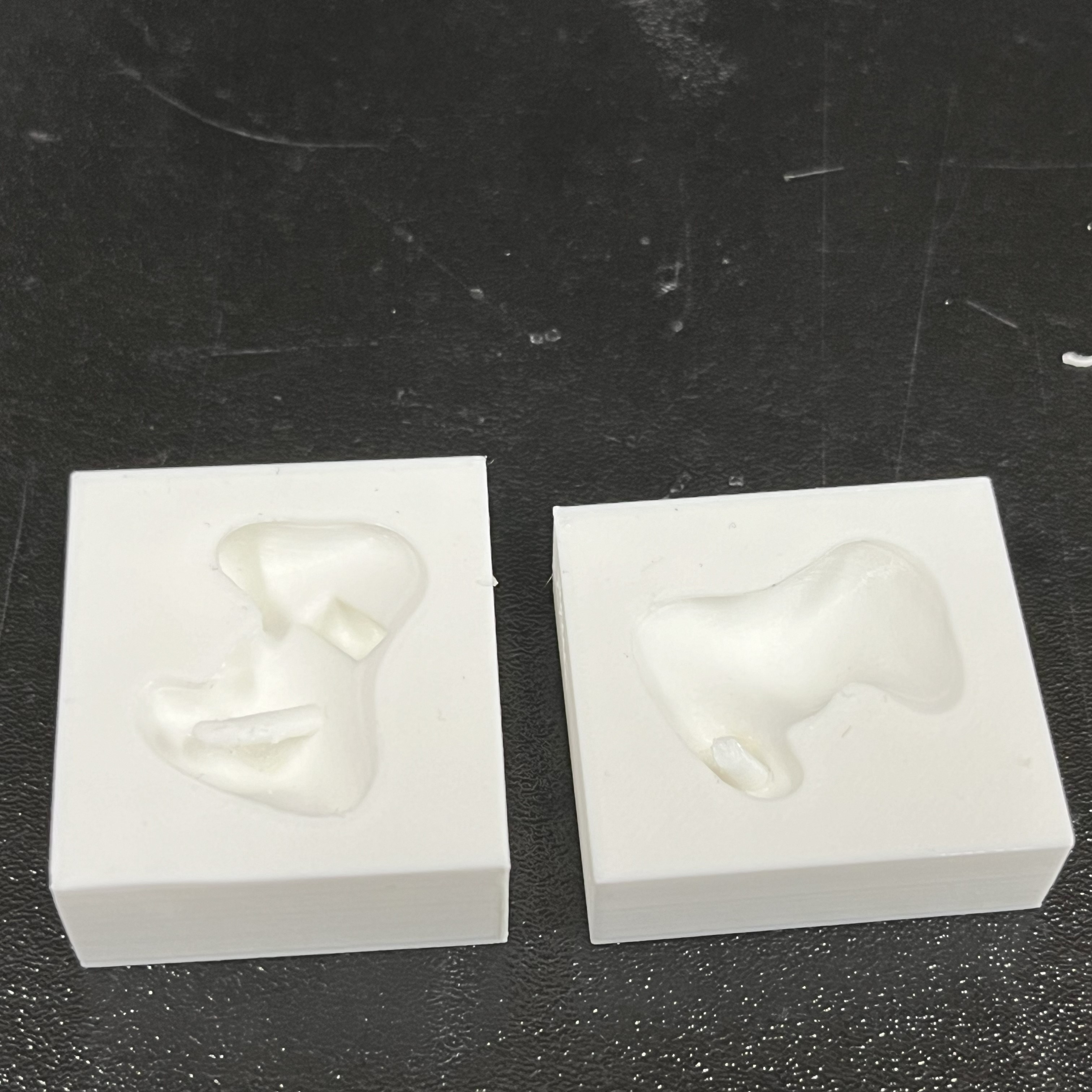 Image of two white, 3D-printed box casts for an earmold.