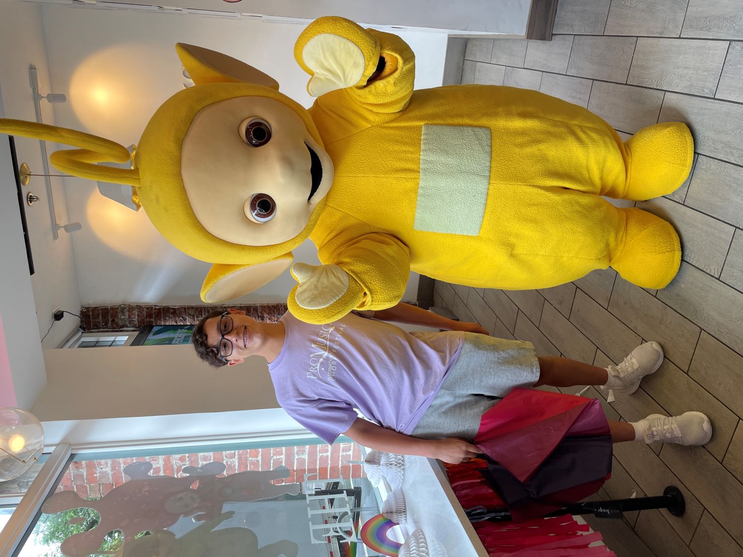 LaaLaa, the yellow Teletubby, and I standing together inside of a donut shop.