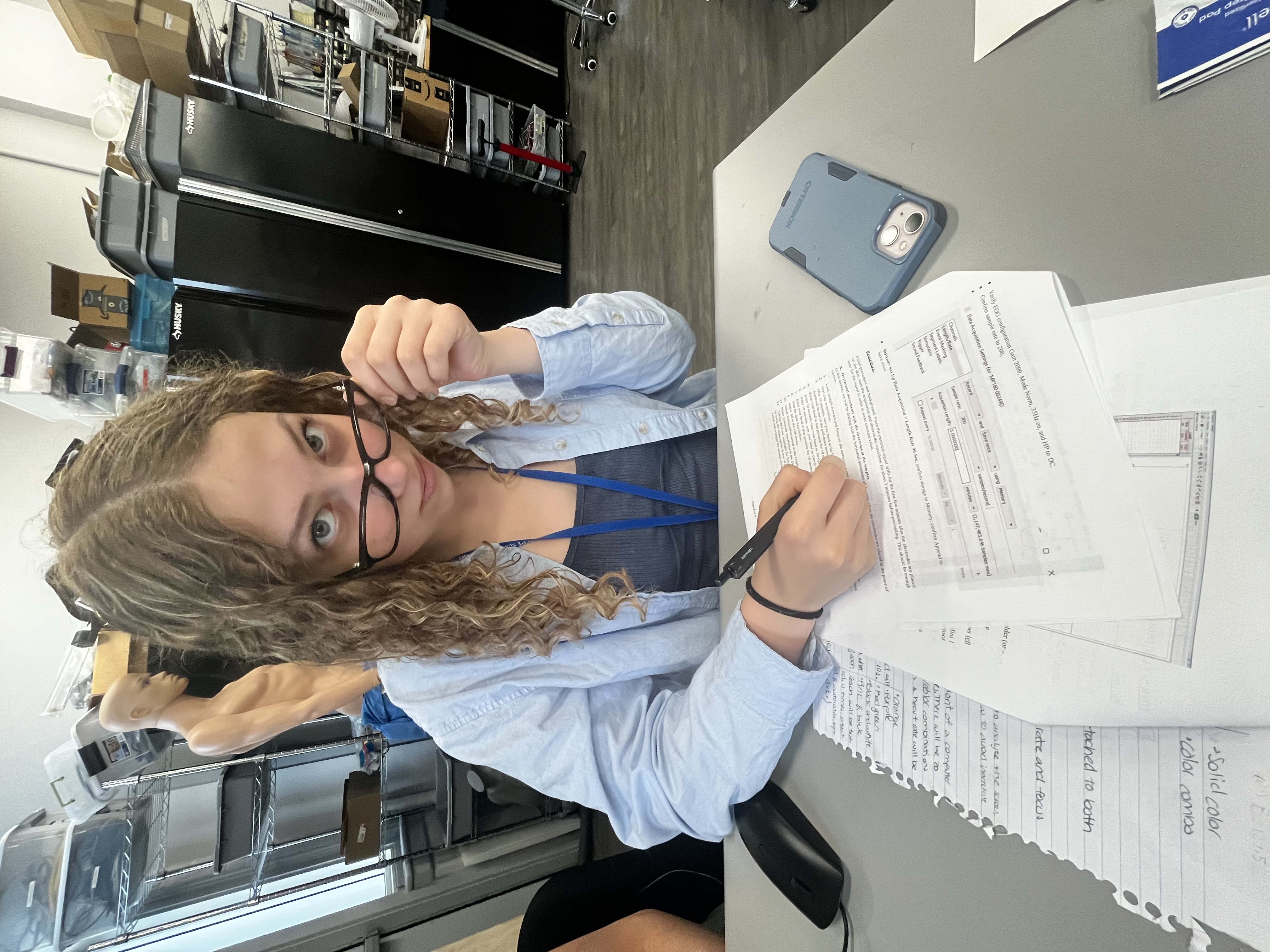 =Girl lowering glasses on nose, writing on paper