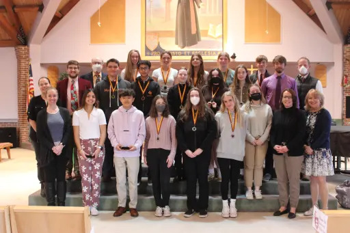 Lindsey and other science fair winners standing in the chapel holding trophies and medals. 