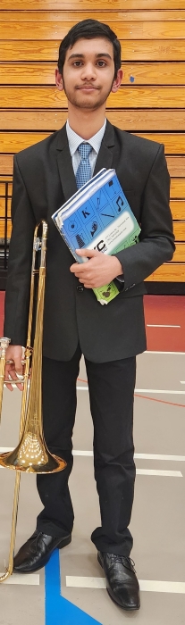 Photograph of Medhansh Choudhury standing with a trombone.