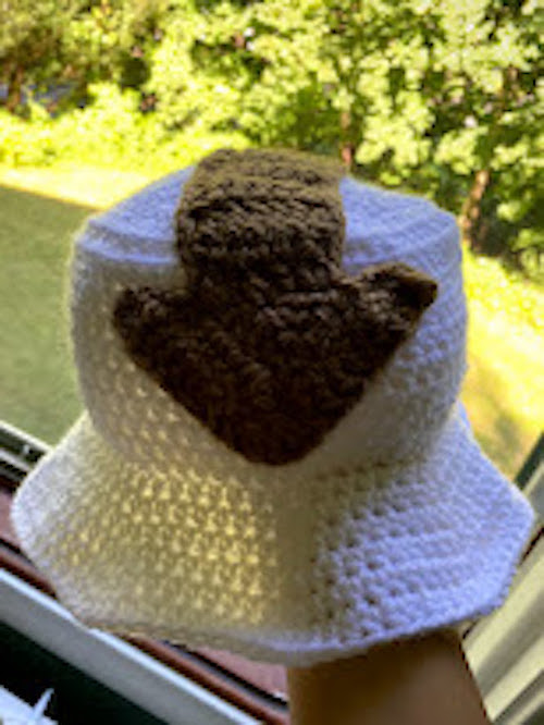 A crochet bucket hat that is white and has Appa's
				arrow on it